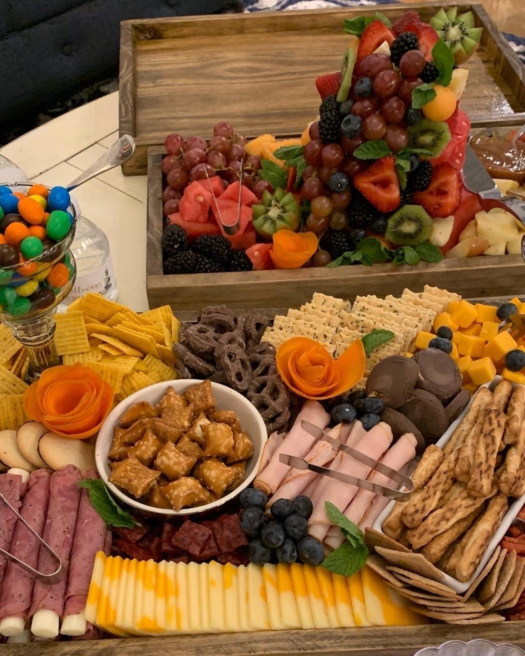 A wooden tray filled with a variety of snacks and fruit.