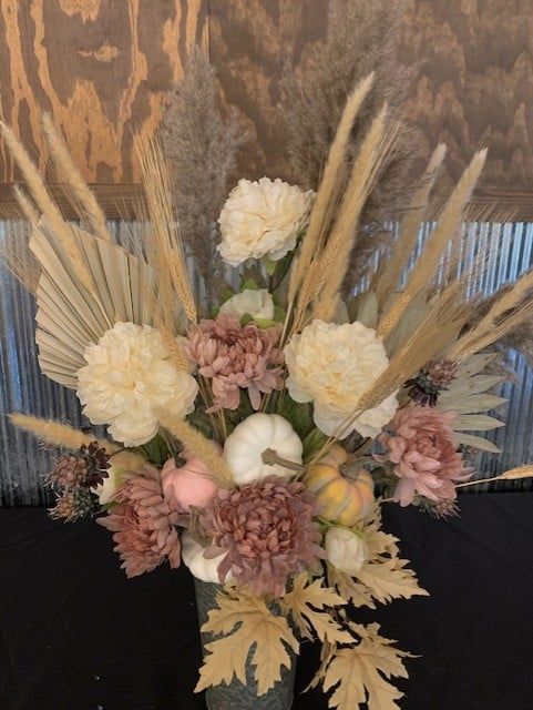 A vase filled with flowers and pumpkins is sitting on a table.