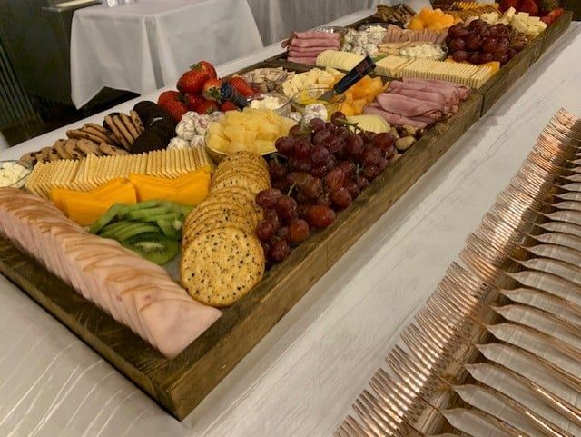 A wooden tray filled with a variety of food and crackers on a table.