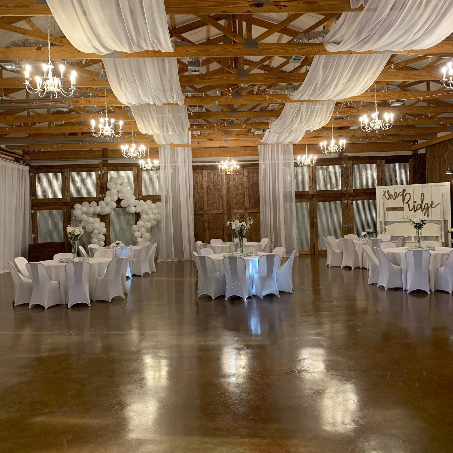 A large room with tables and chairs set up for a wedding reception.