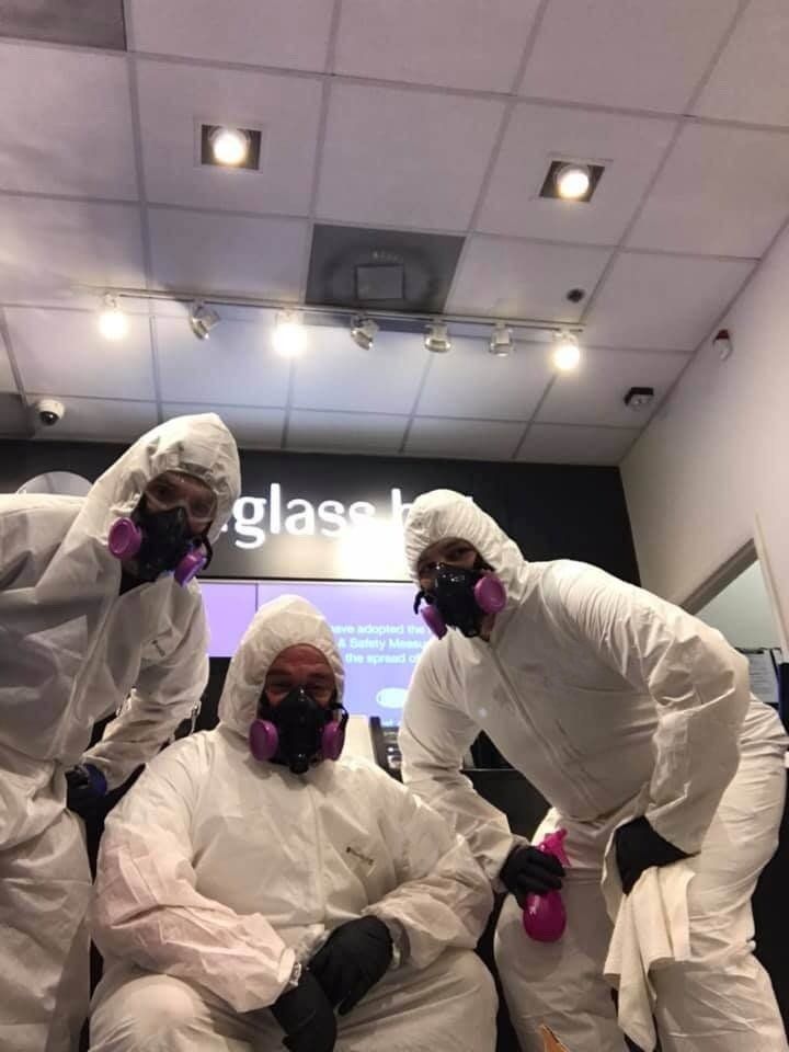 A group of people in protective suits are posing for a picture in a store.