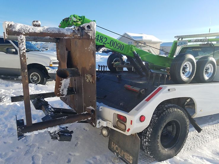 A tow truck is carrying a green motorcycle on a trailer.