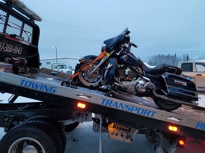 A motorcycle is sitting on top of a towing truck.