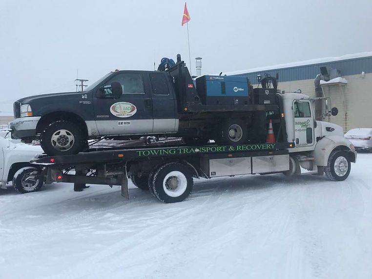 A tow truck is towing a truck in the snow.