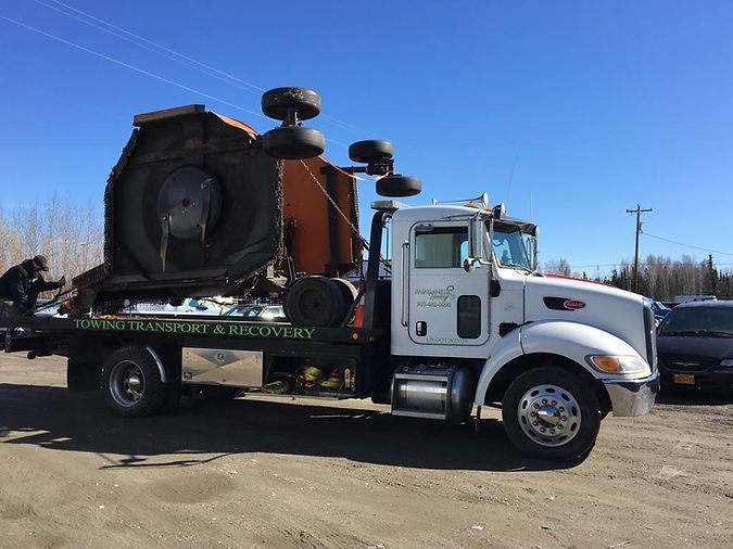 A tow truck with a large tire on the back of it