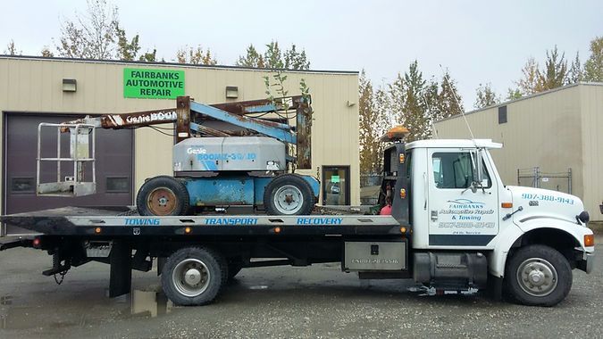 A tow truck with a lift on the back is parked in front of a building.
