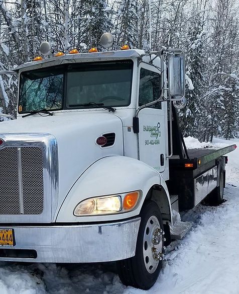 A white tow truck is parked in the snow.