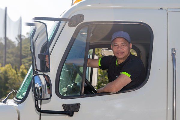 A man is sitting in the driver 's seat of a truck.