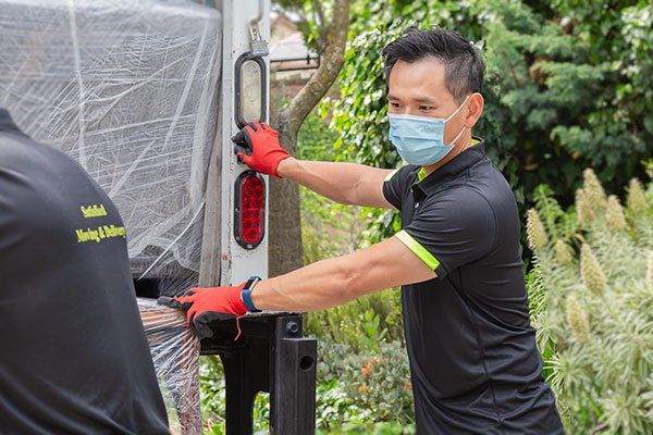 A man wearing a mask and gloves is loading a truck.
