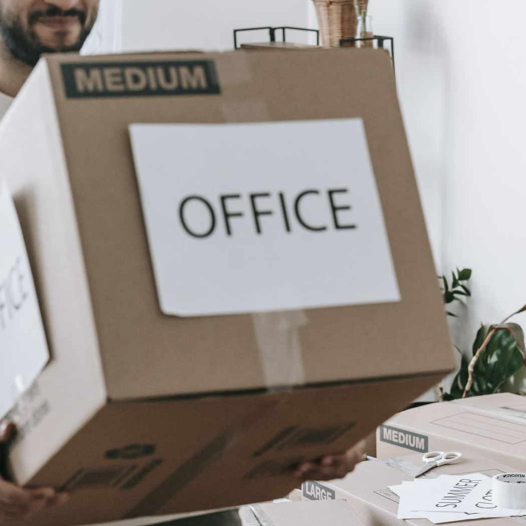 A man is carrying a cardboard box labeled medium office