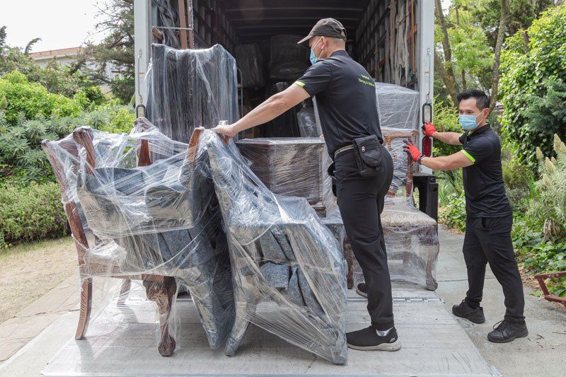 Two men are loading furniture into a truck.