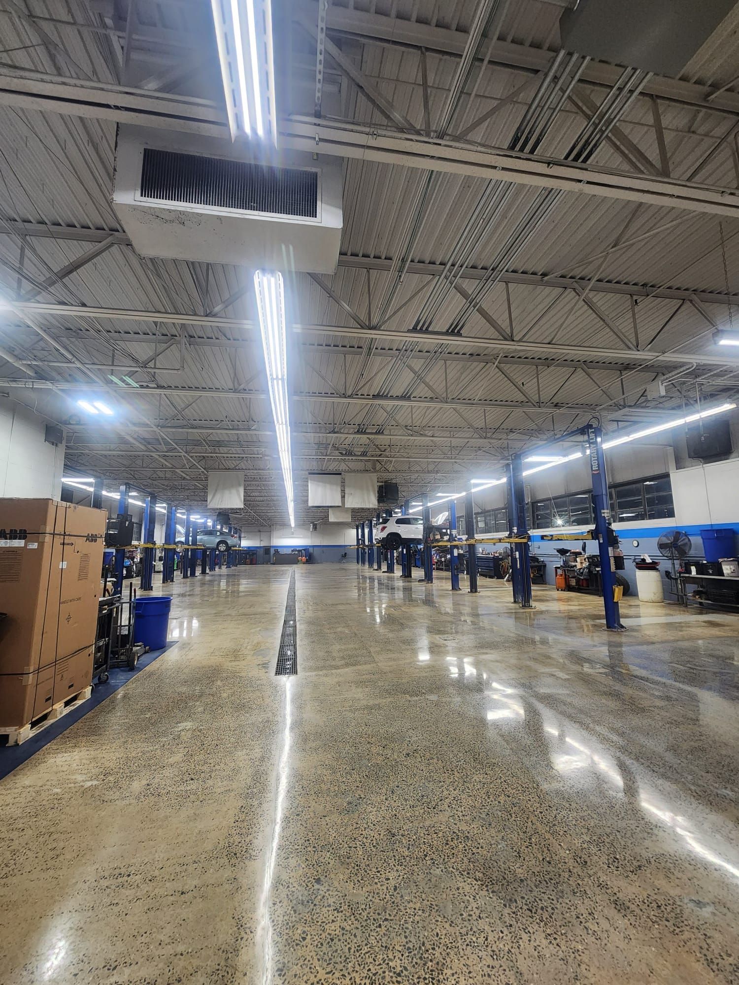 A large warehouse with a lot of lights and boxes on the floor.