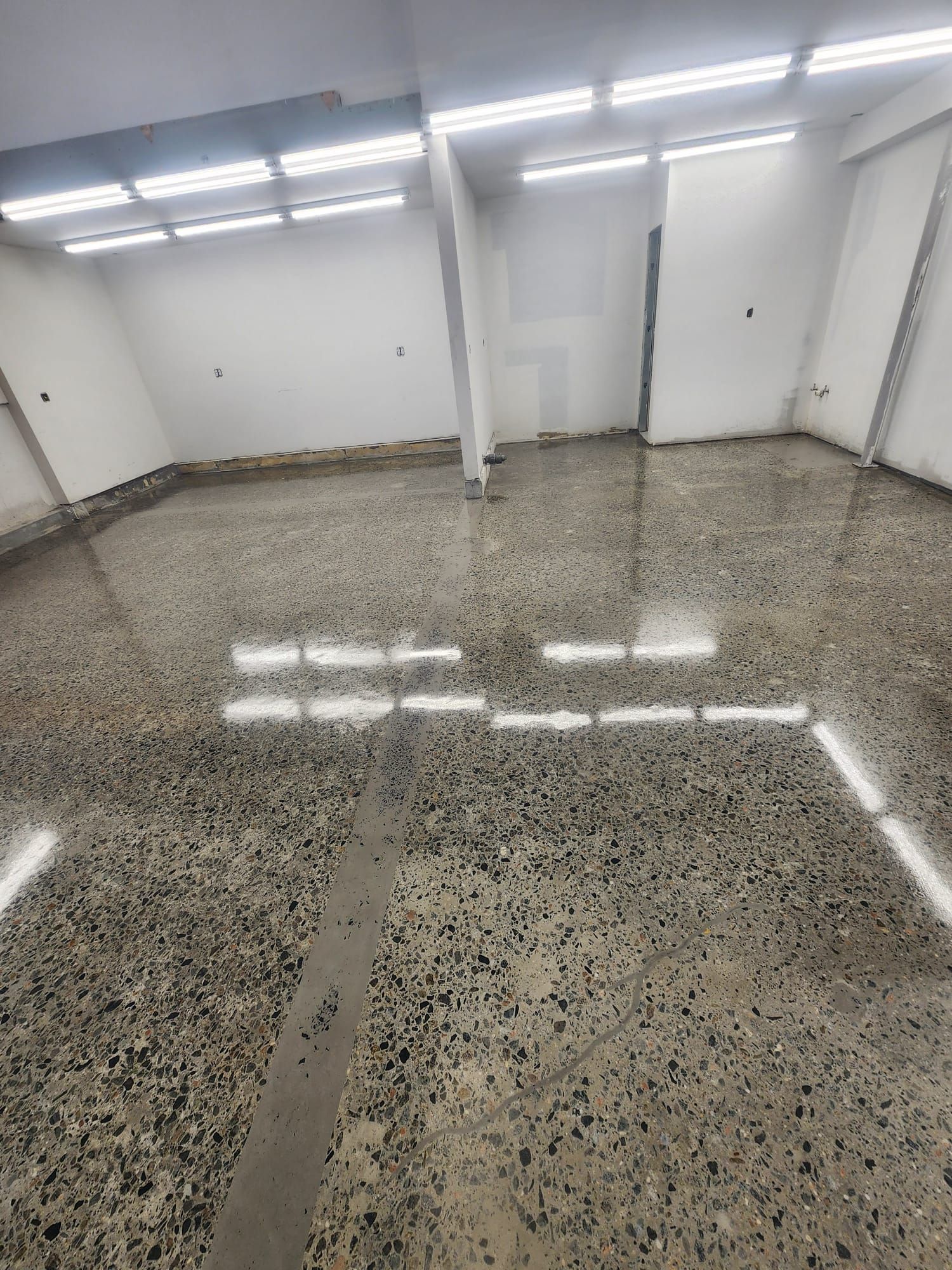A large empty room with a shiny concrete floor and white walls.