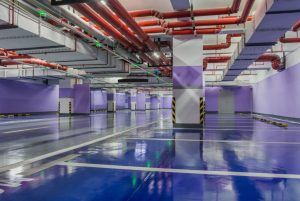 An empty underground parking garage with purple walls and blue floors.