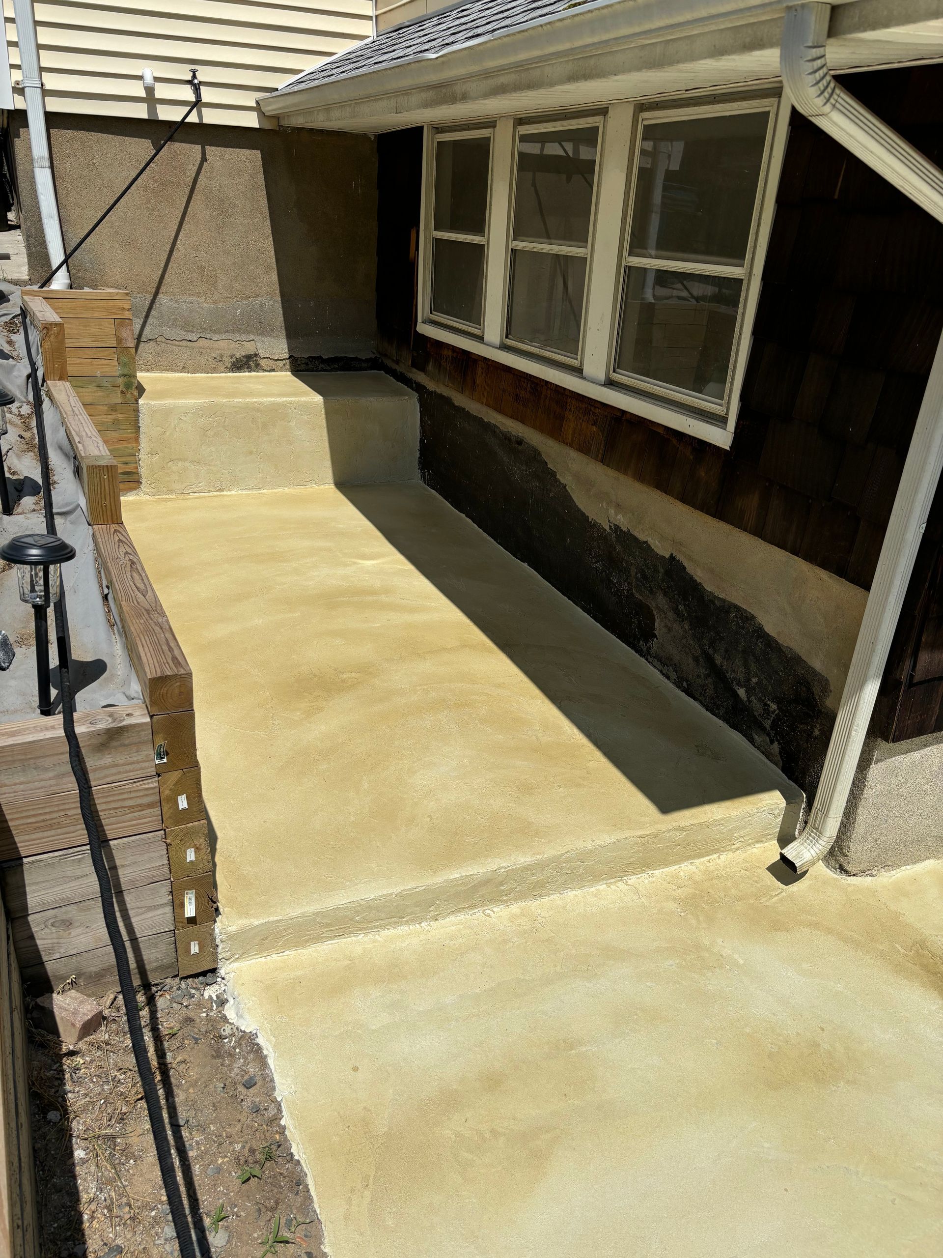 A concrete walkway is being built in front of a house.
