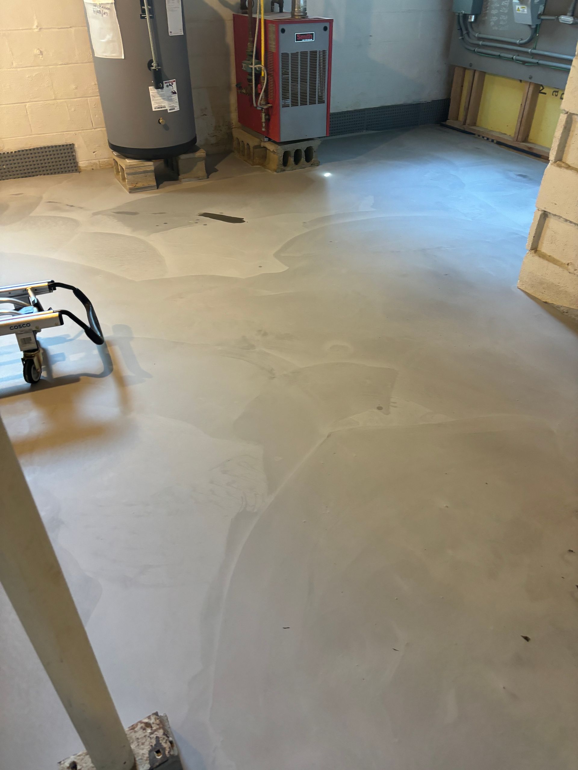 A room with a water heater and a furnace on the floor.