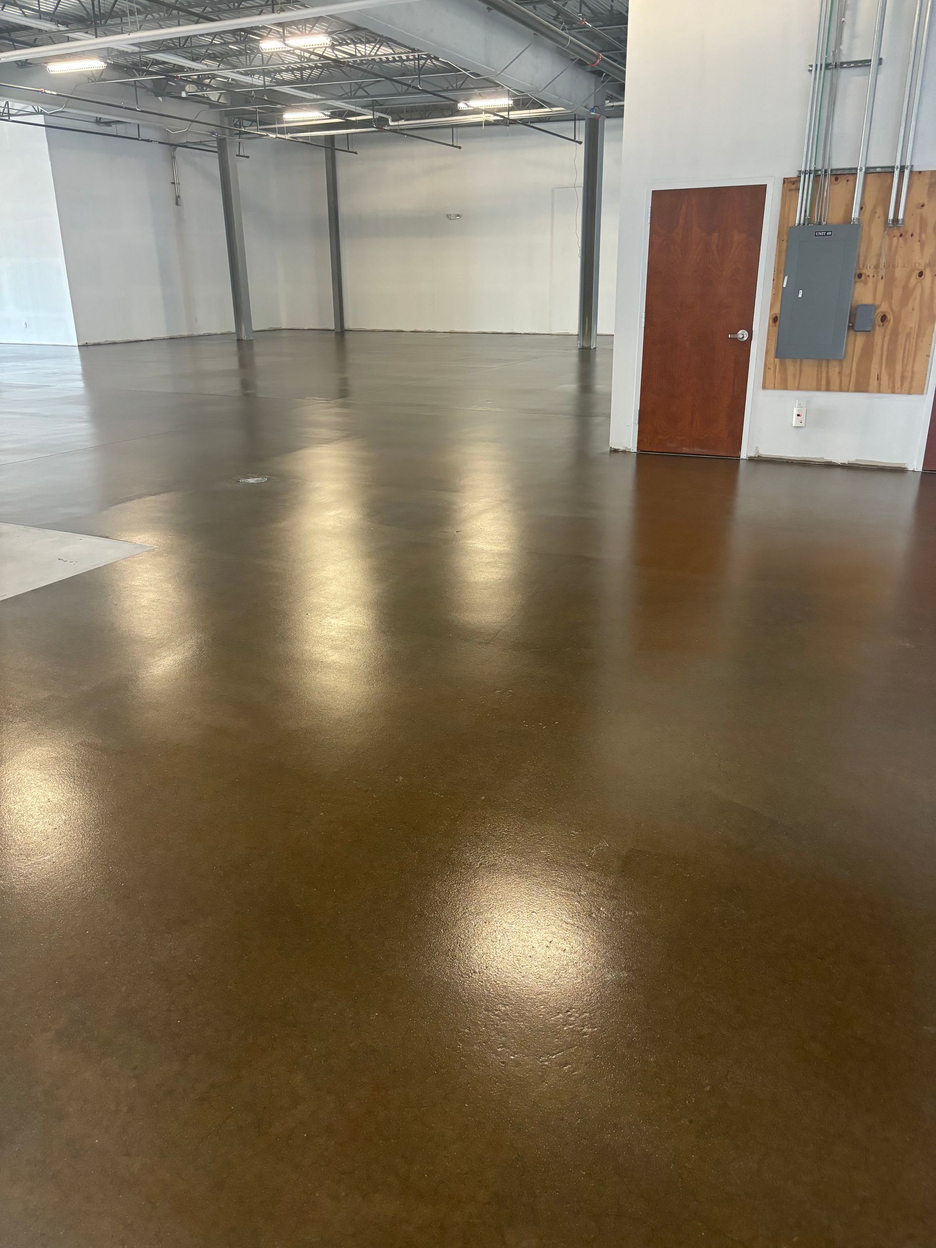 A large empty room with a brown floor and white walls.