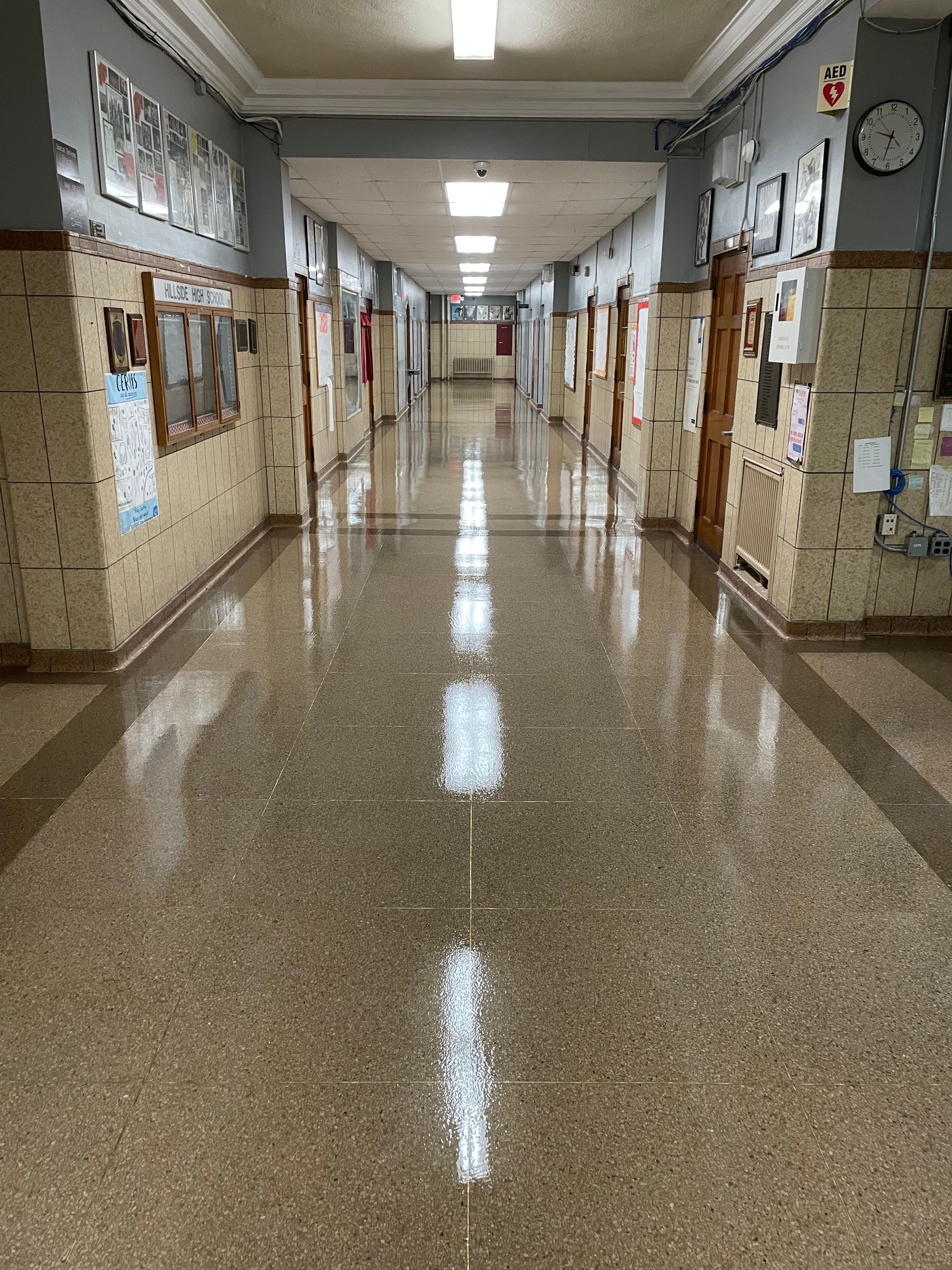 A long hallway in a building with a clock on the wall.