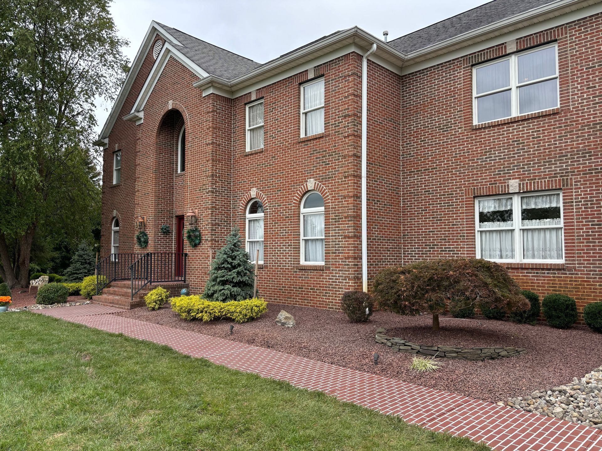 A large brick house with a brick walkway leading to it.