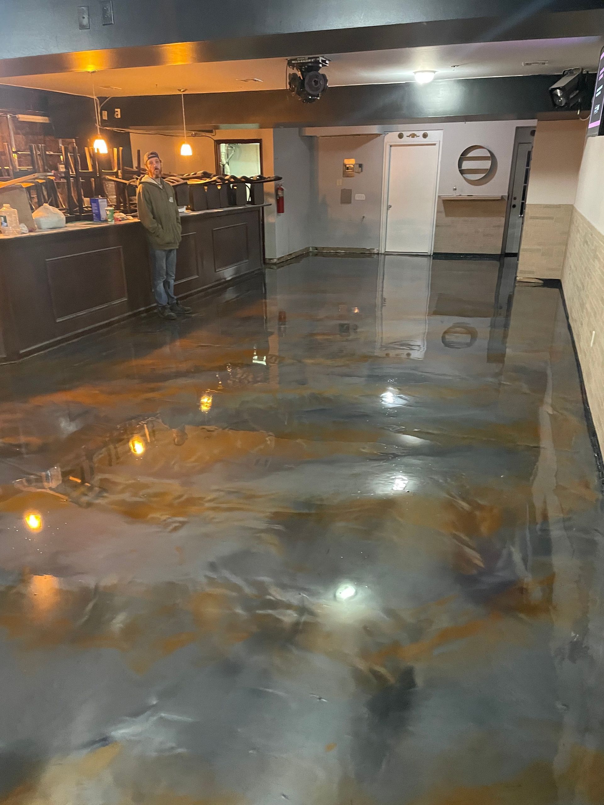 A man is standing in a room with a shiny metallic floor.