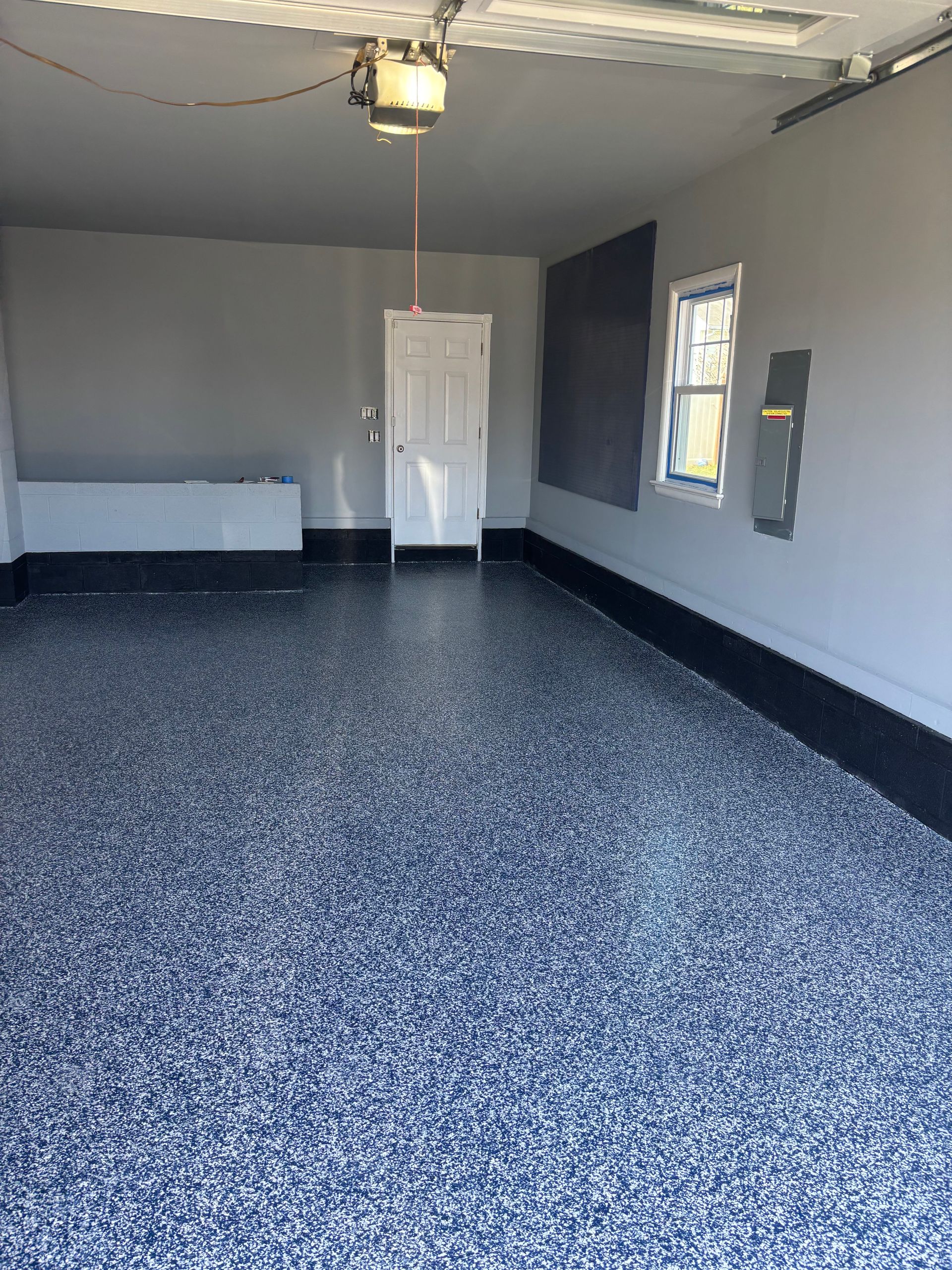 A garage with a gray and blue floor and a door.