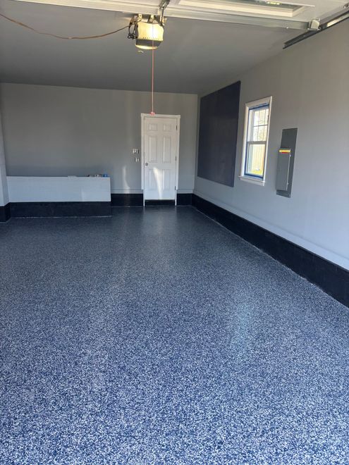 A garage with a gray and blue floor and a door.