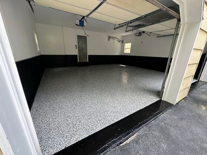 A garage with a black and white floor and a garage door open.