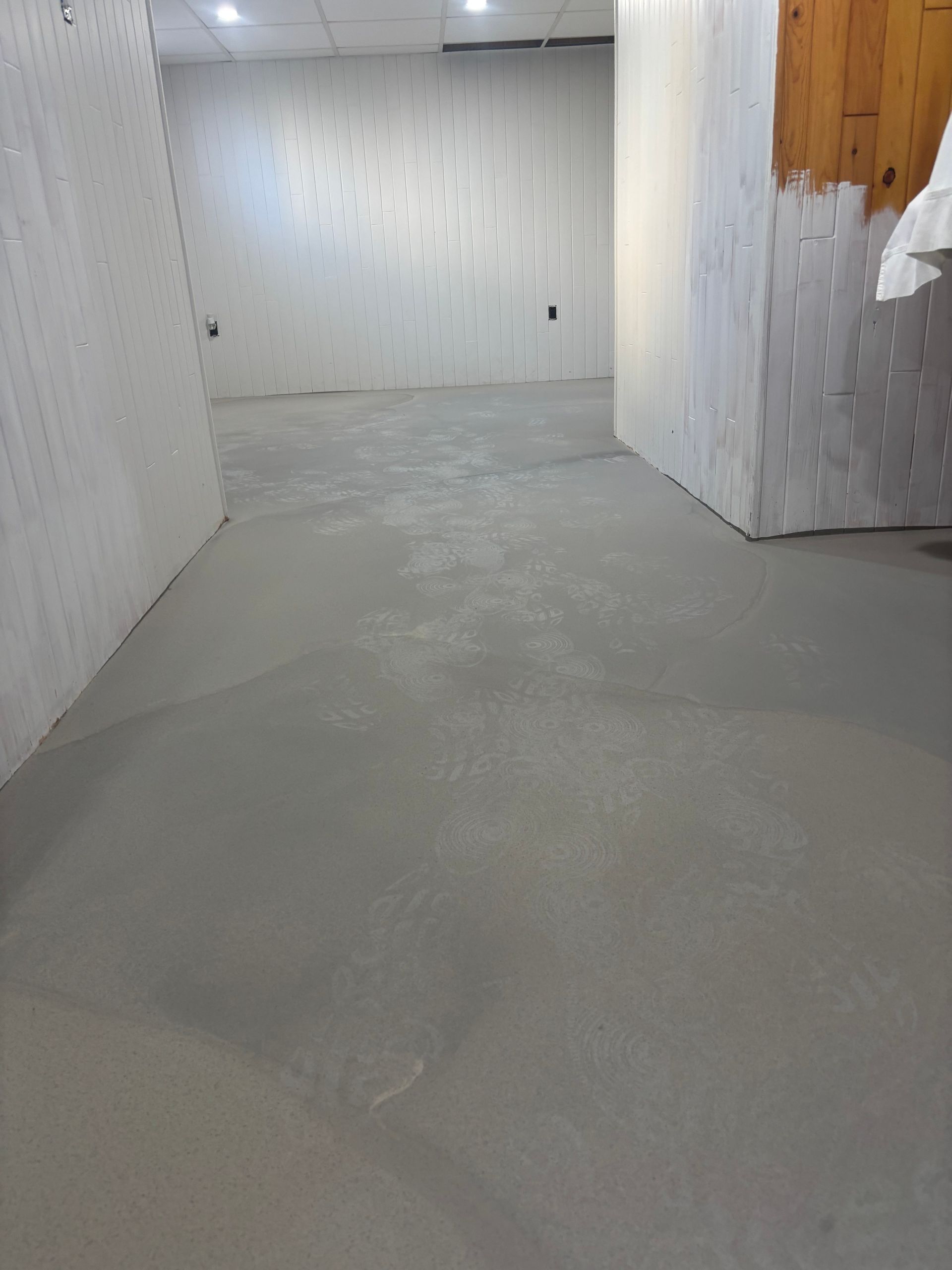 A large empty room with a concrete floor and white walls.