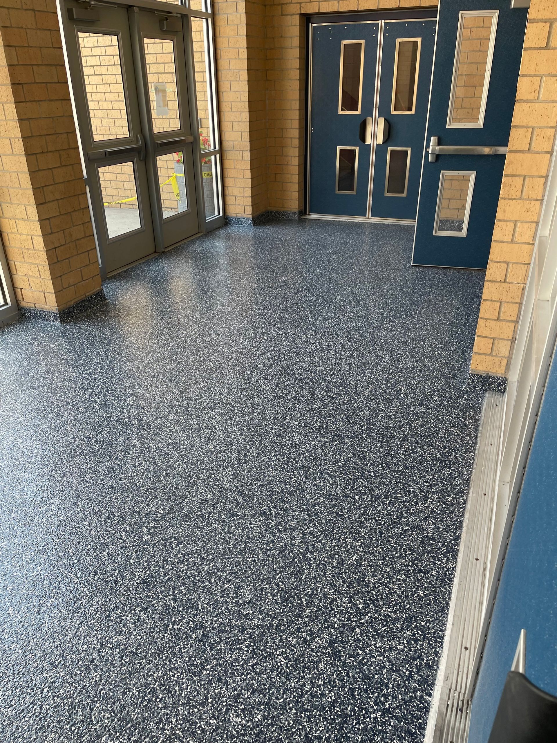 A hallway with a blue door and a brick wall.