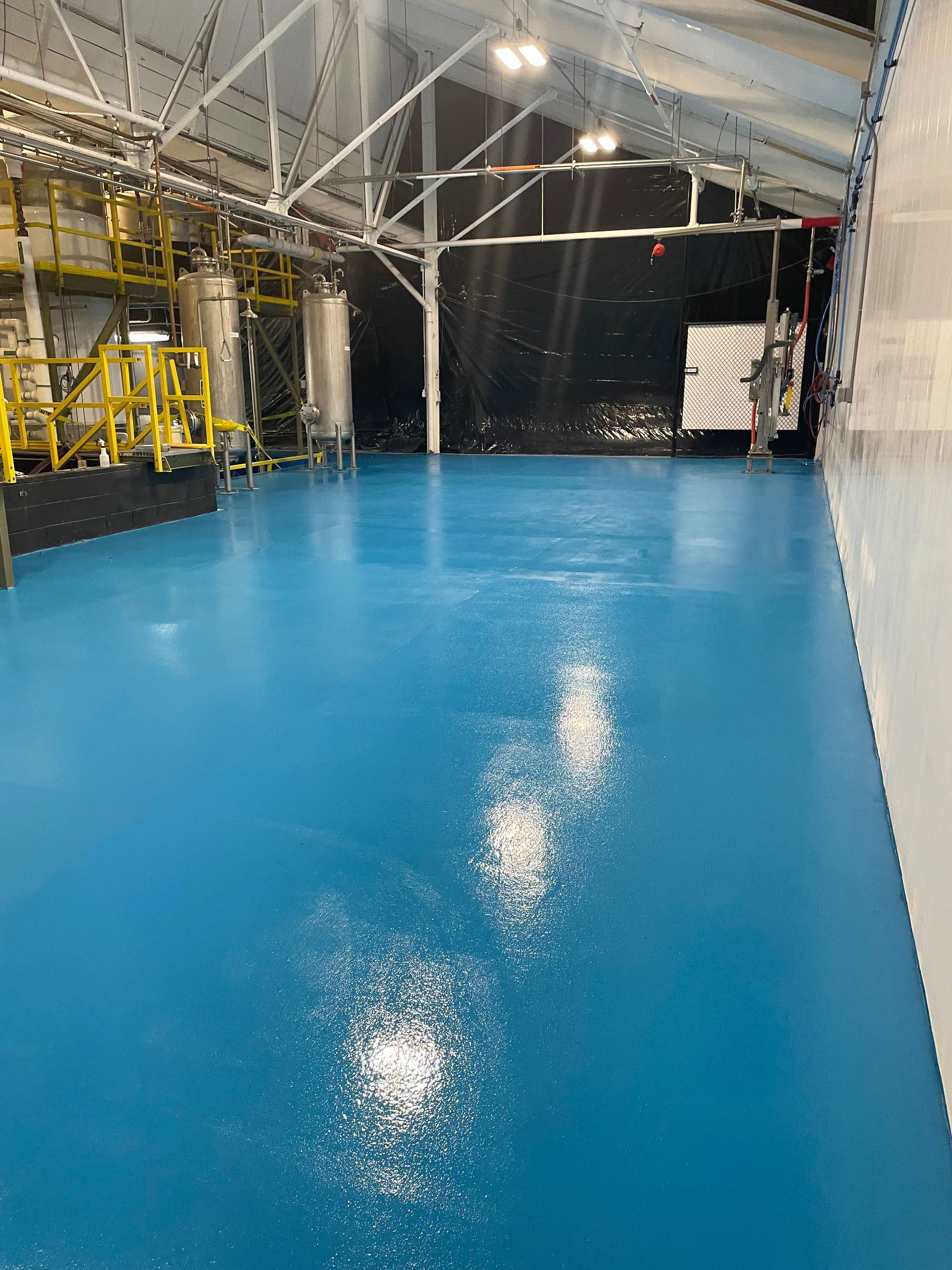 A large warehouse with a blue floor and yellow machinery.