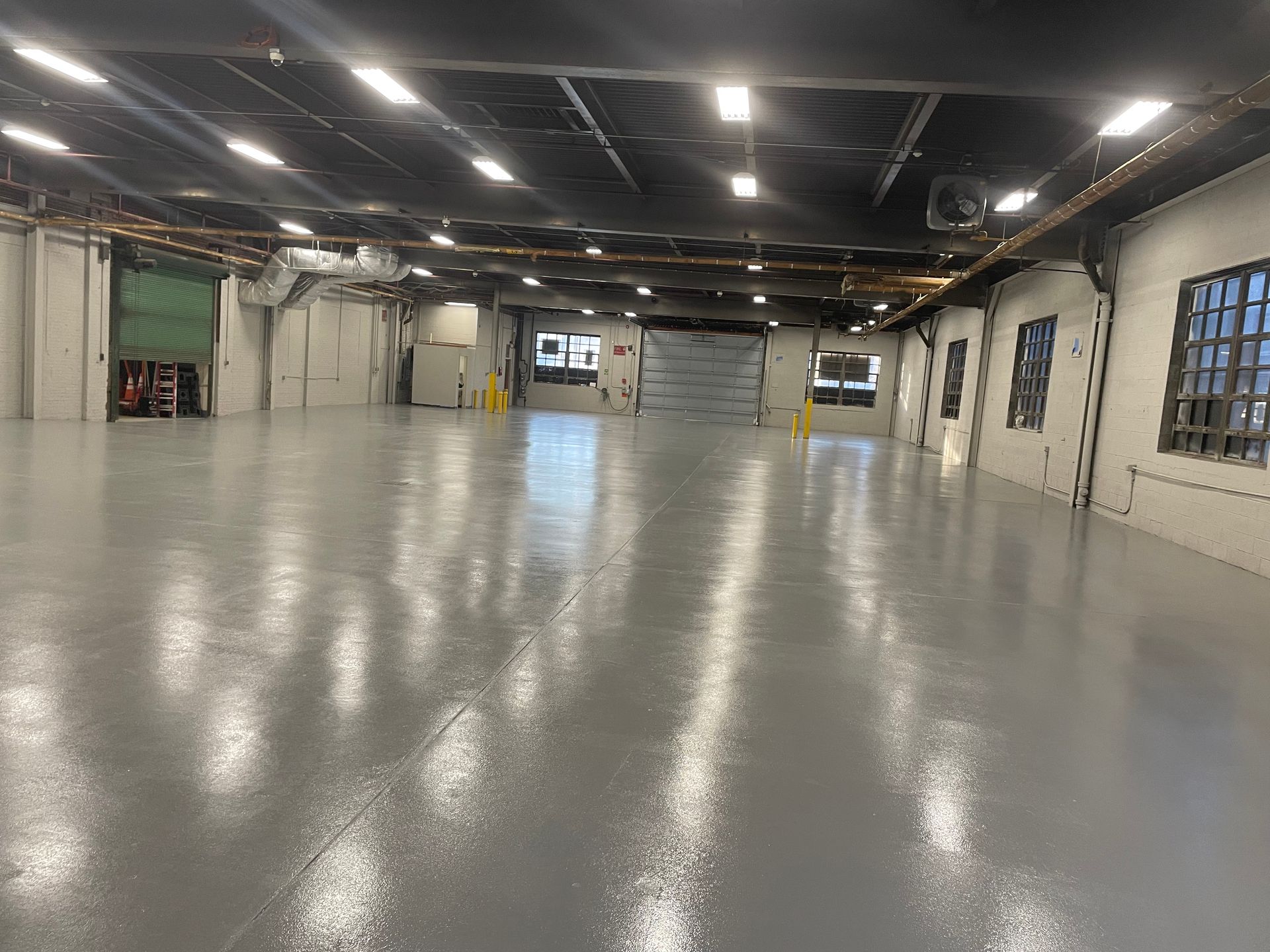 A large empty warehouse with a concrete floor and lots of windows.