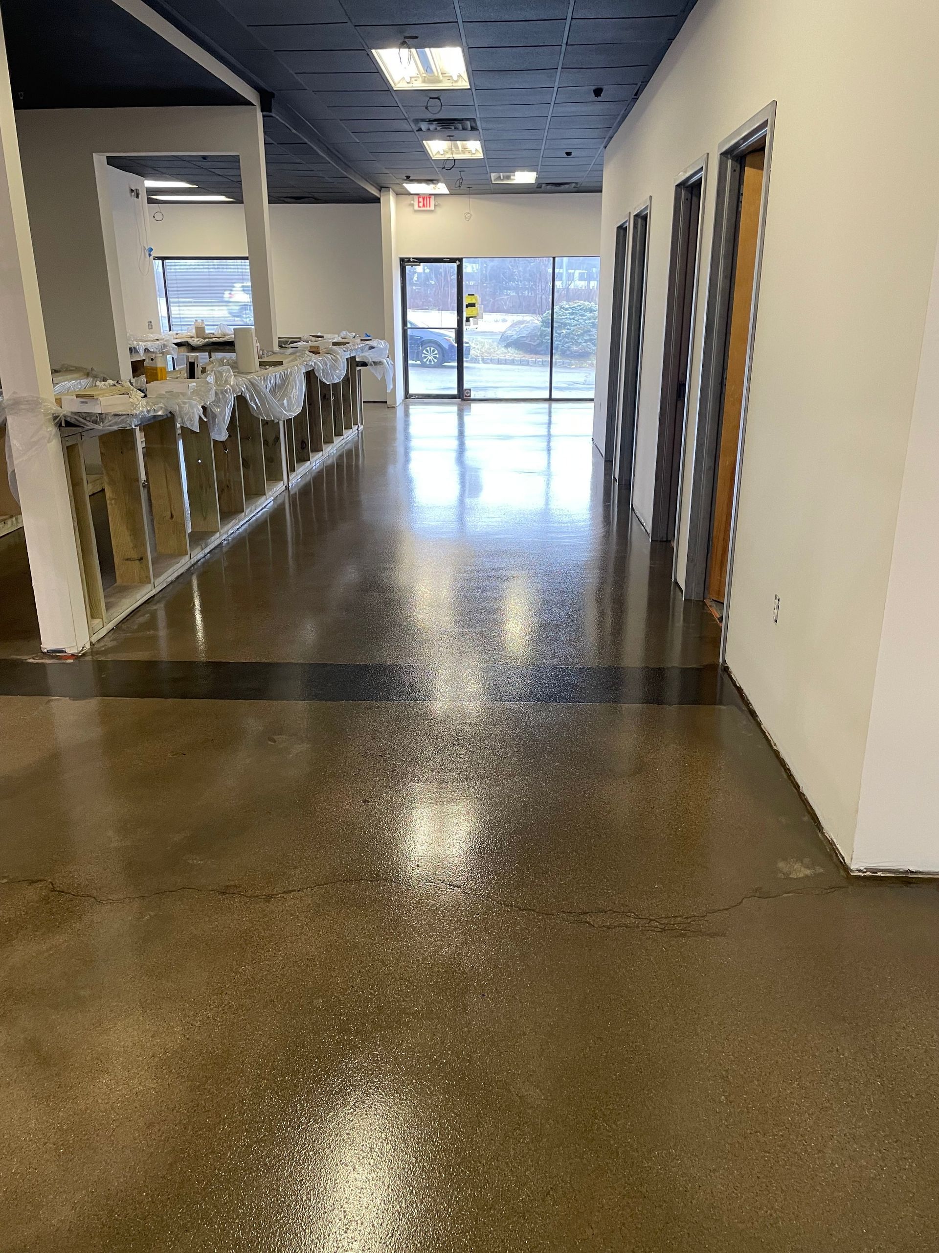 A long hallway with a shiny concrete floor in a building under construction.