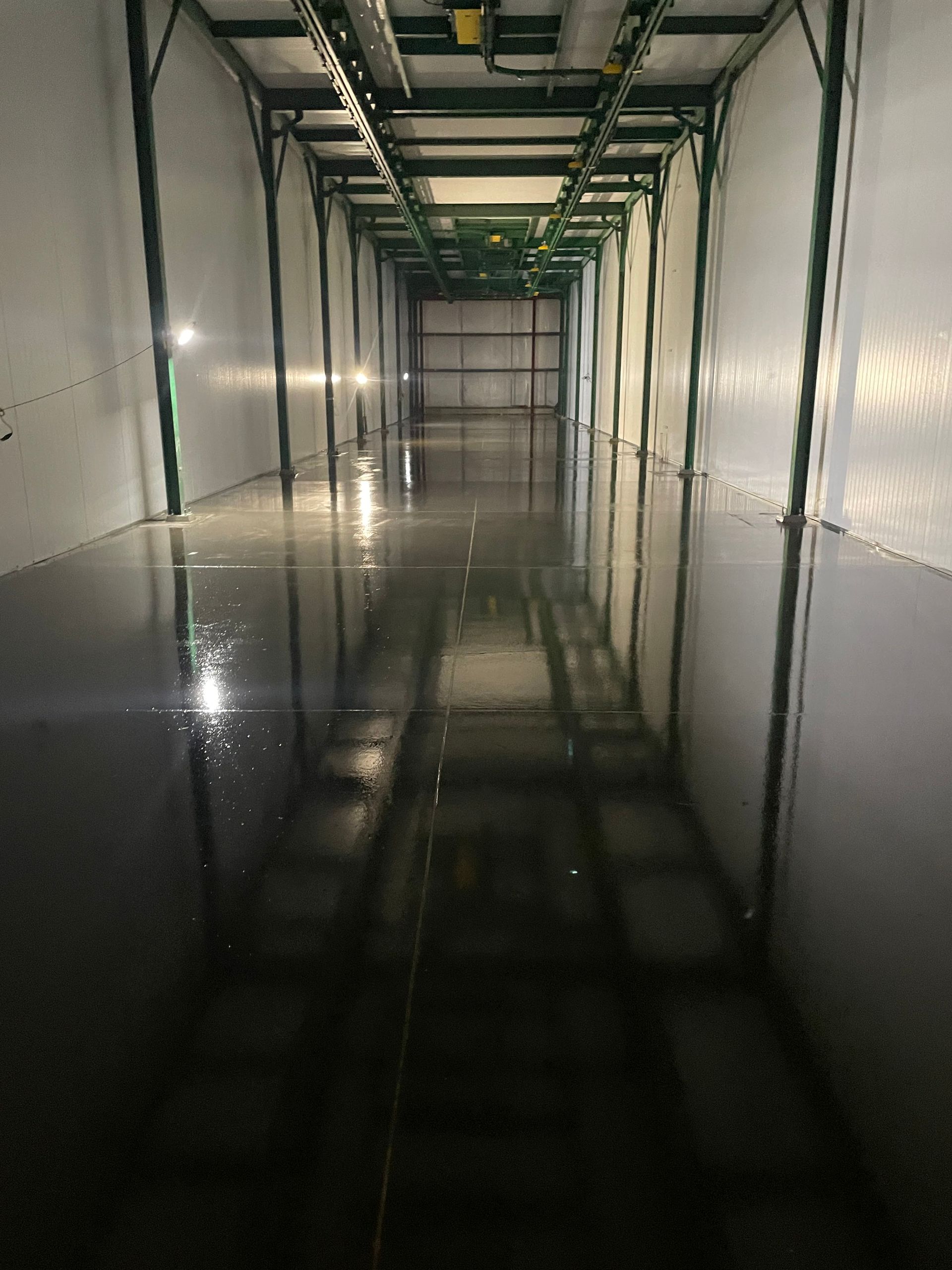 A long hallway with a reflection of a building in the floor.