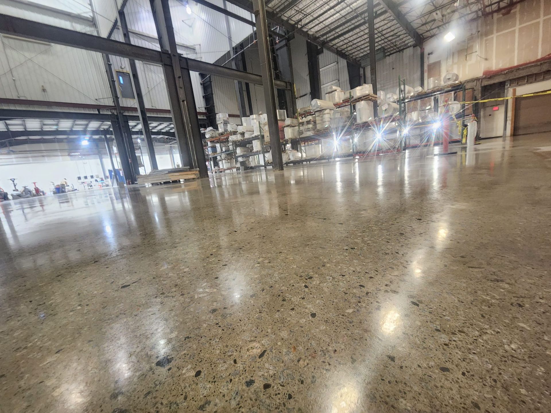 A large warehouse with a shiny concrete floor and lots of shelves.