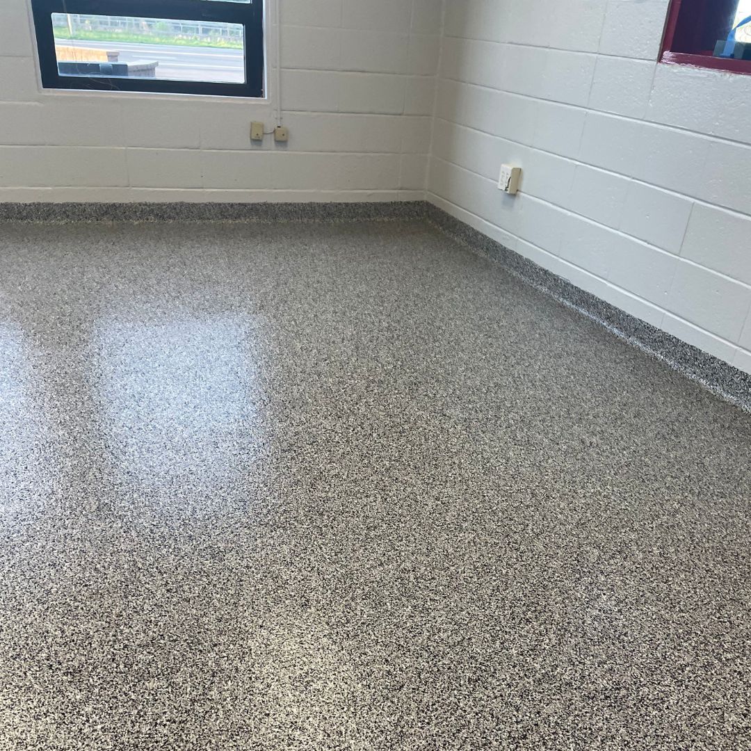 A room with a gray floor and white brick walls.