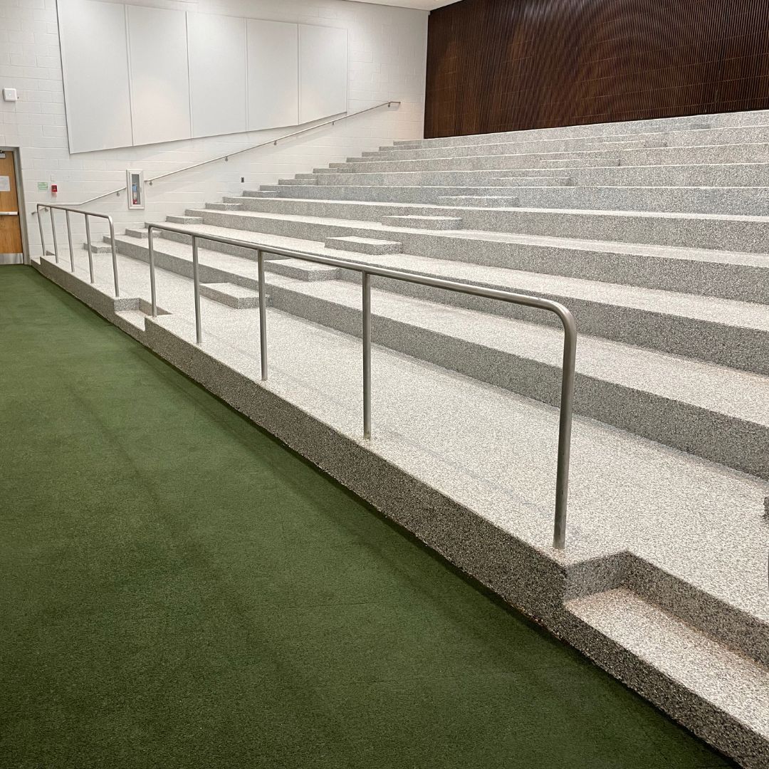 A long row of stairs in an auditorium with a metal railing.