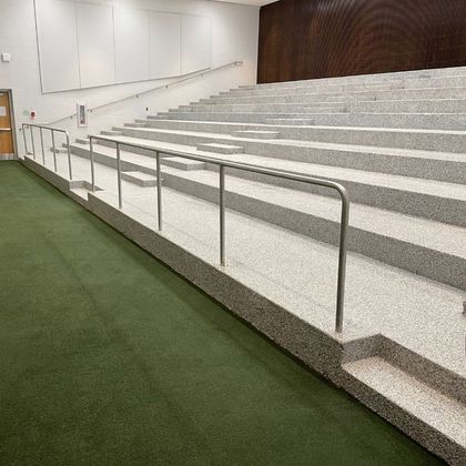 A long row of stairs in an auditorium with a metal railing.