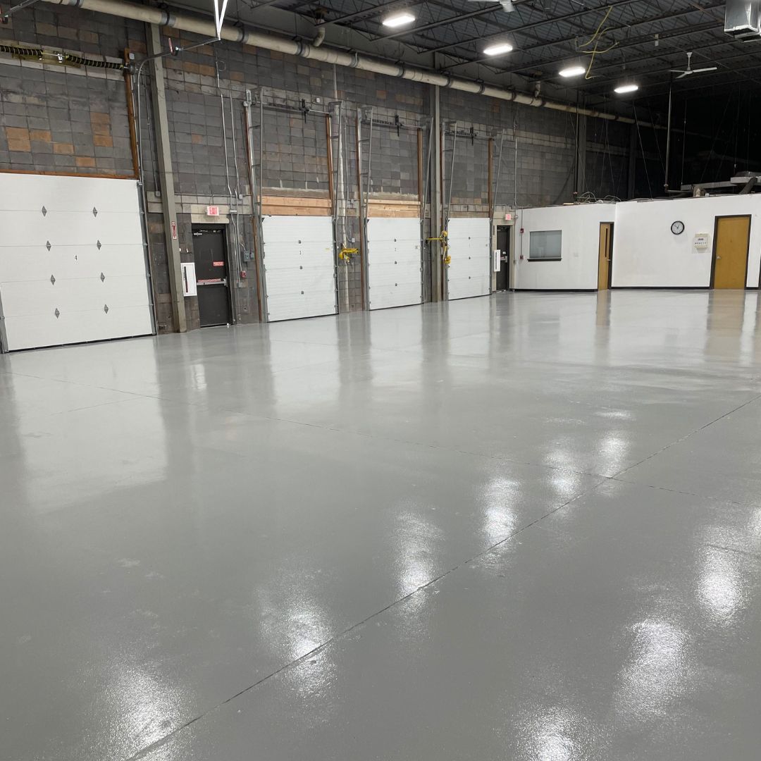 A large warehouse with a lot of doors and a gray floor.