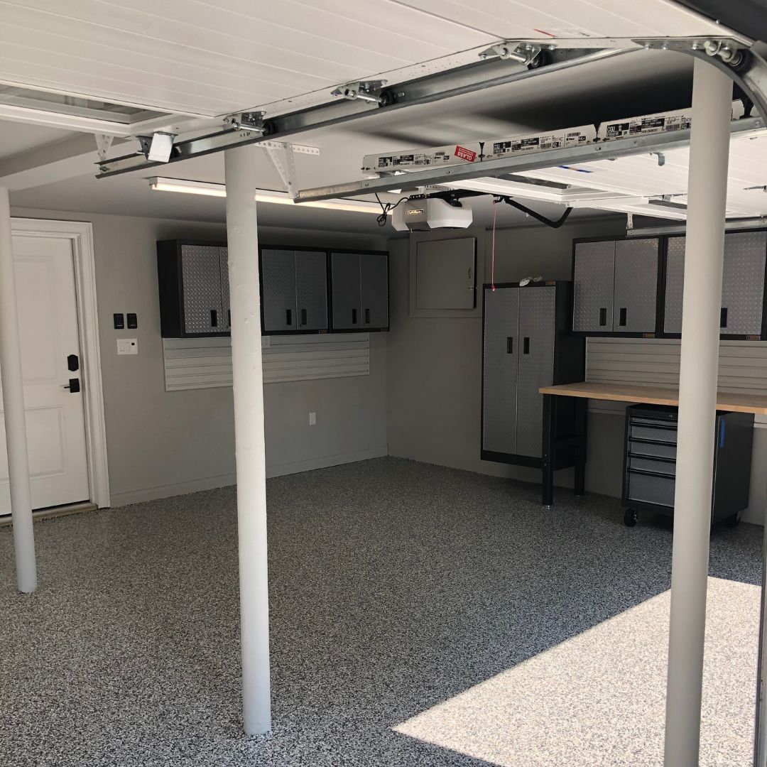 A garage with a garage door open and a table and cabinets.