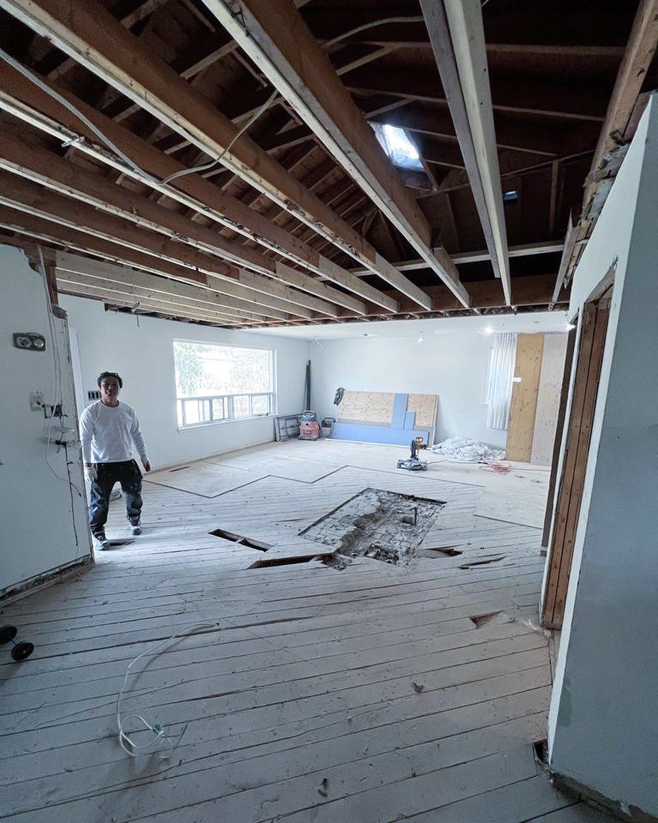 Man in black shirt holding coffee mug, smiling in a kitchen.