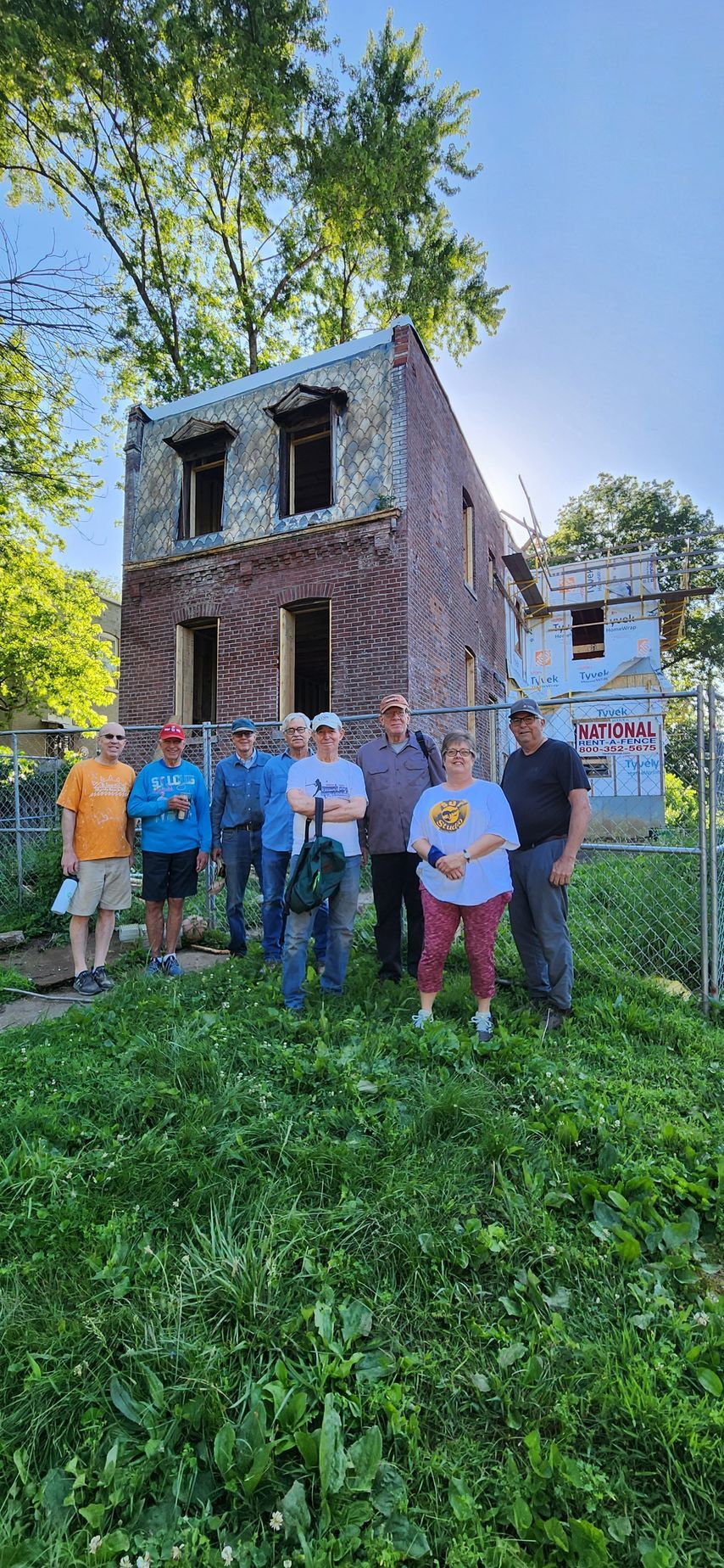 Group of people standing in front of a  brick building on Habitat for Humanity work day.