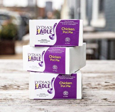 Three stacked boxes of Lydia's Ladle Chicken Pot Pie on a wooden surface outdoors.