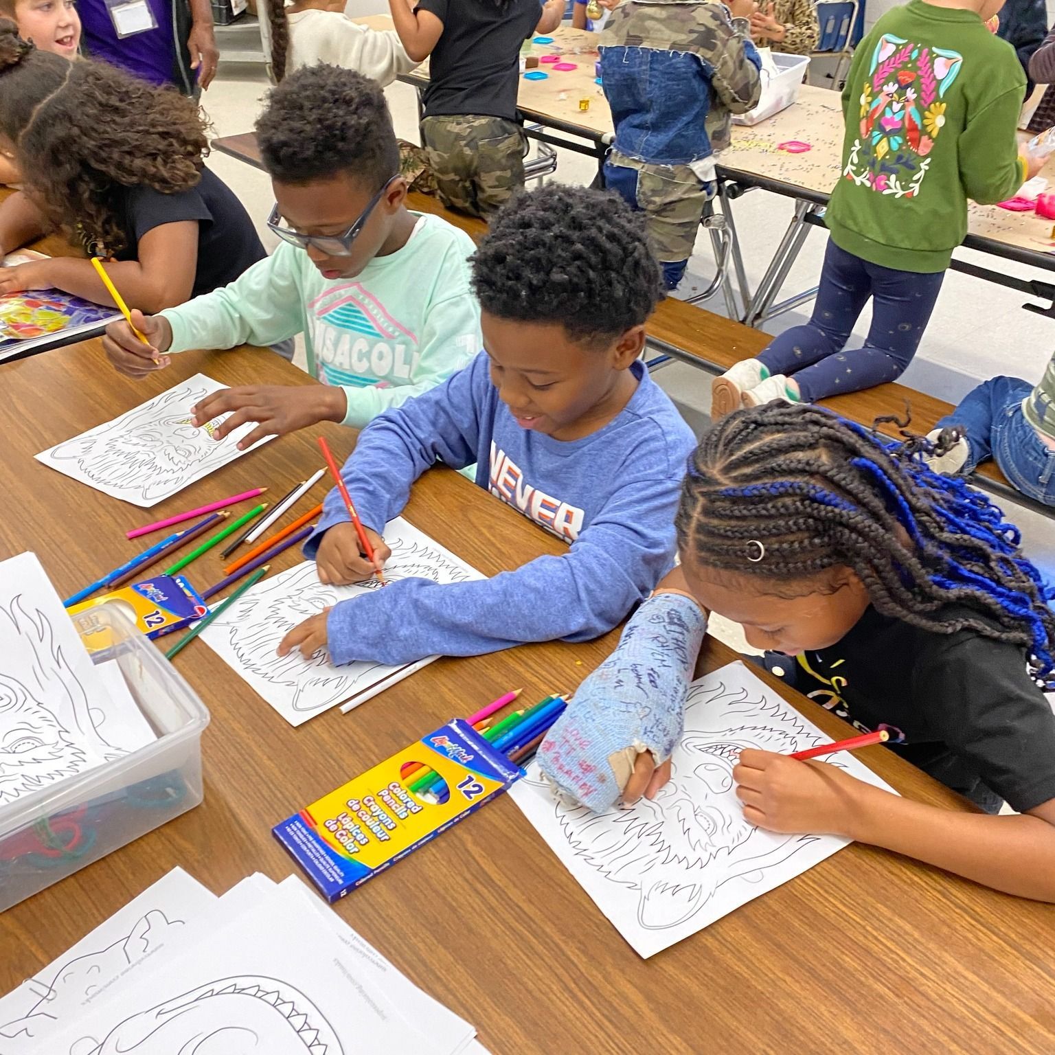 Children coloring at a table with crayons and coloring pages.