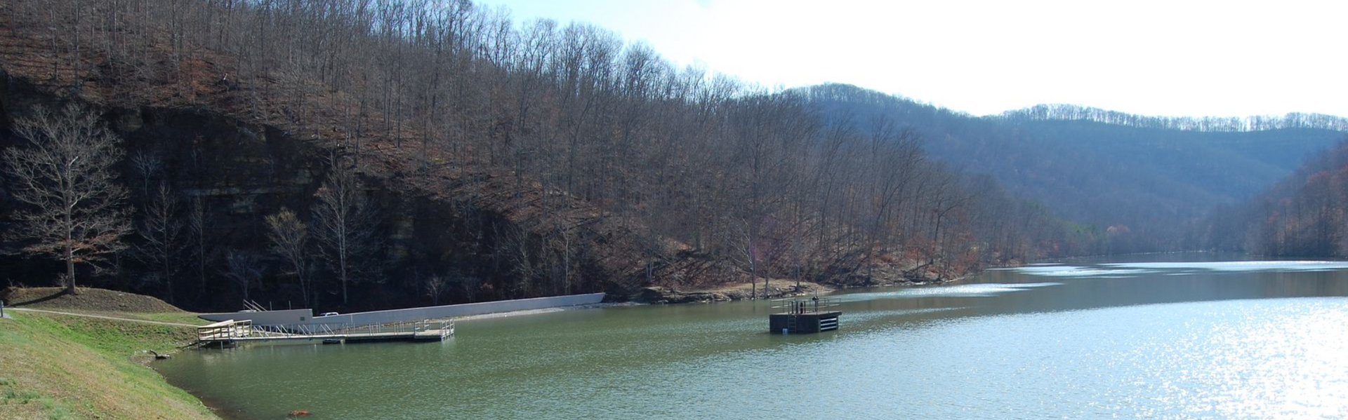 A lake surrounded by mountains with blue hues and trees 