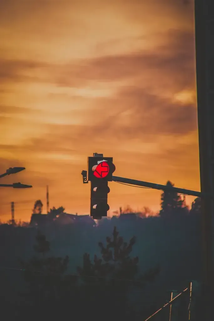 A red traffic light with a sunset in the background.