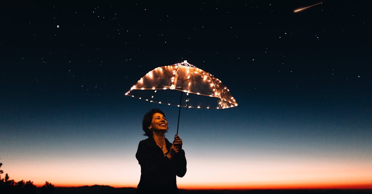 A woman is holding an umbrella made of lights at night.