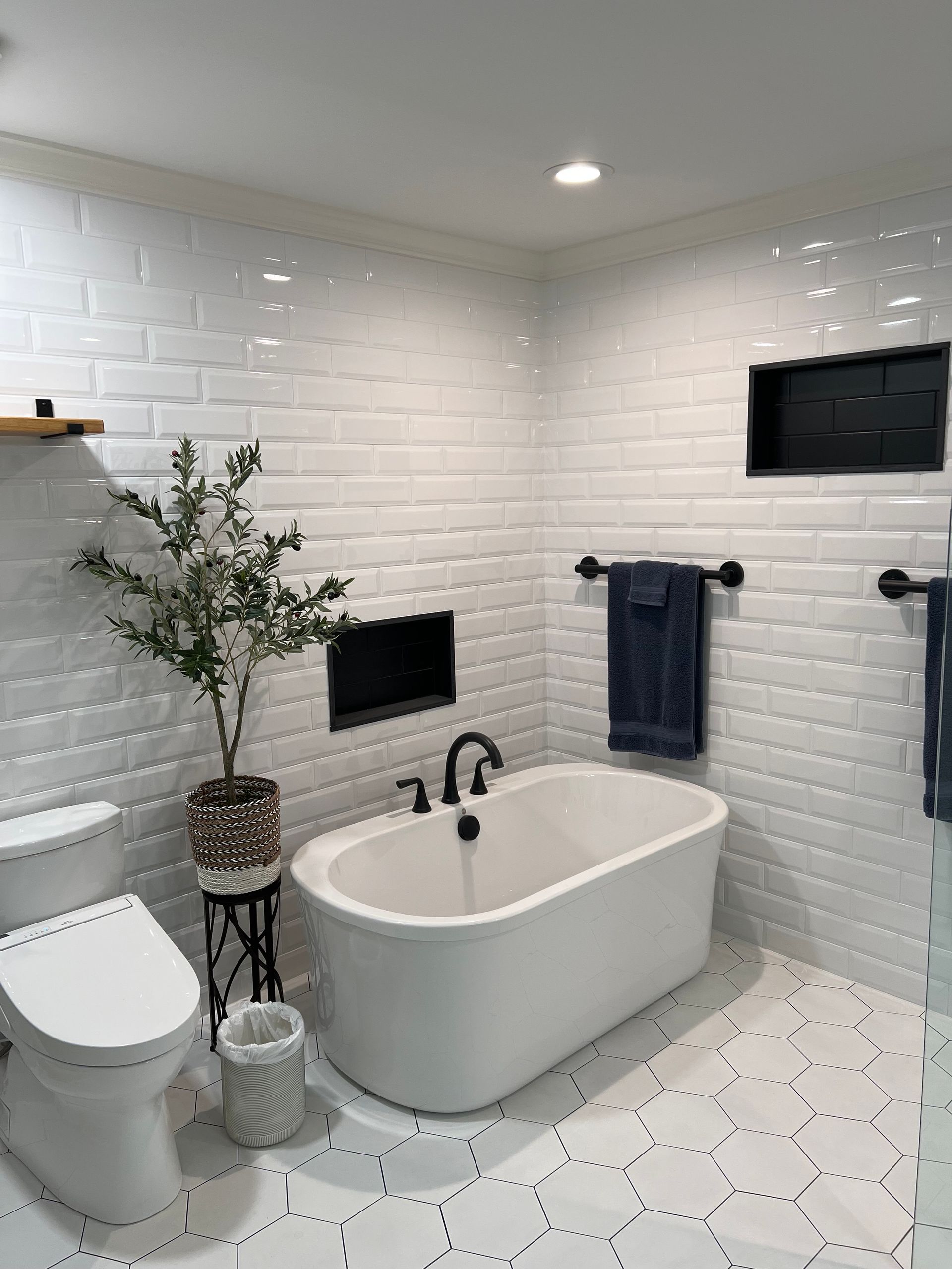 A bathroom with a bathtub , toilet , and plant.