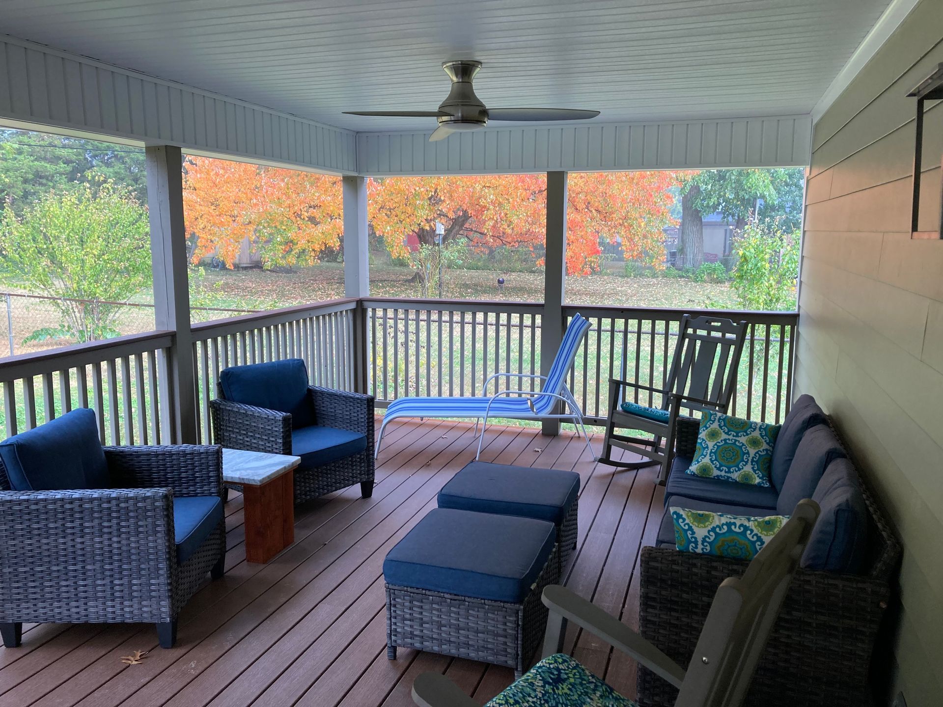 A screened in porch with wicker furniture and a ceiling fan.