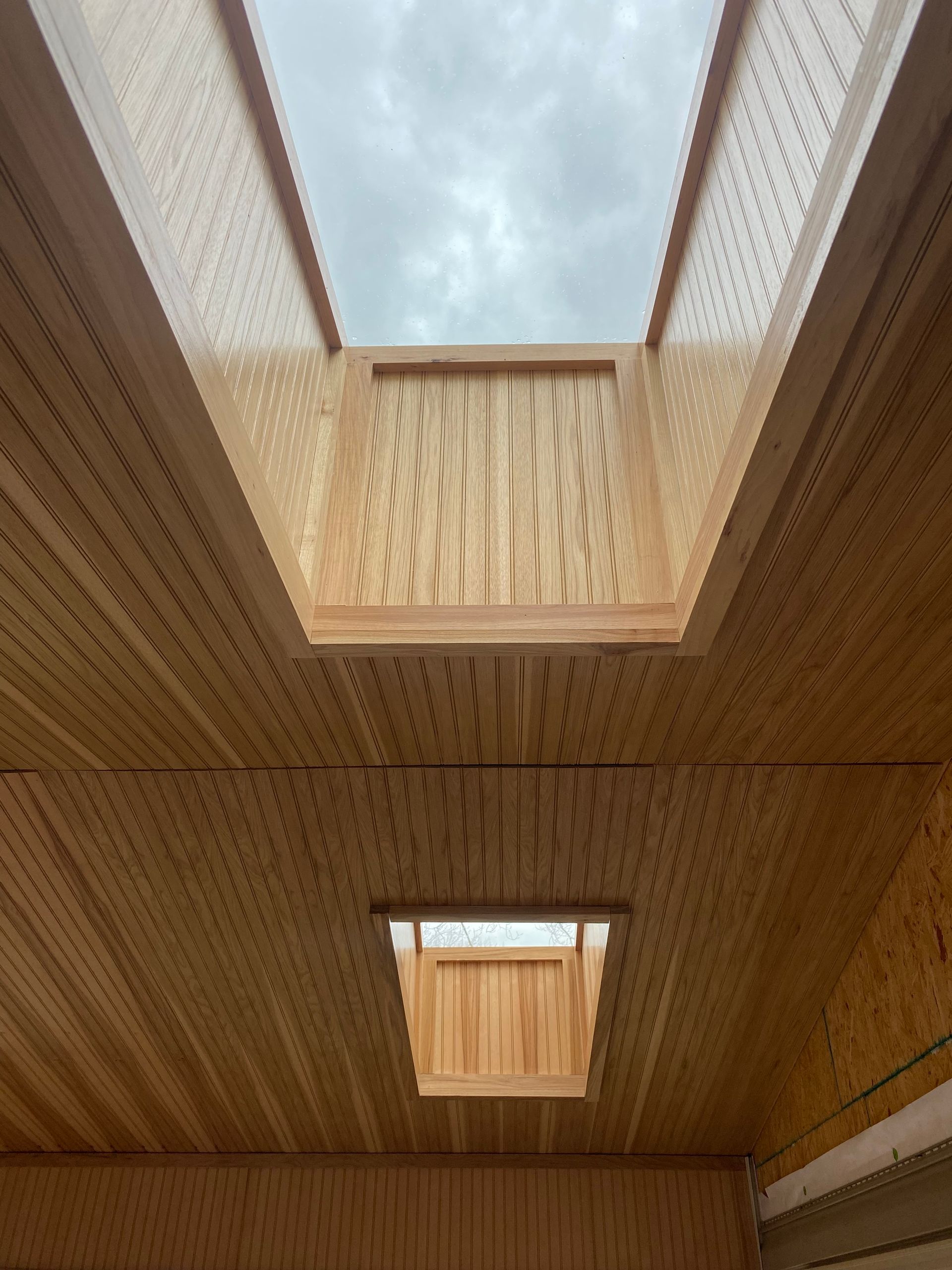 A wooden ceiling with a skylight in the middle of it.