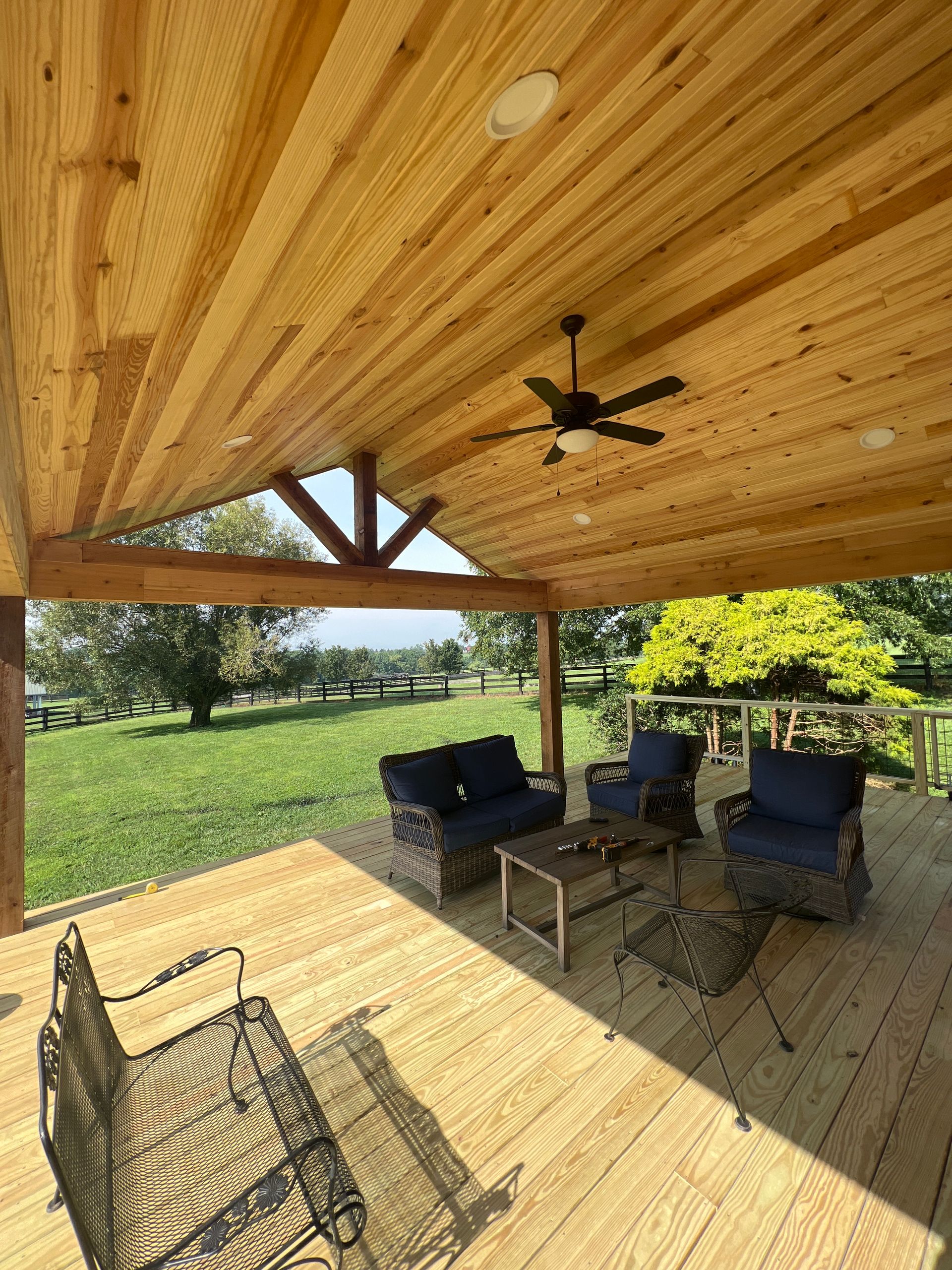 A wooden deck with a ceiling fan and patio furniture.